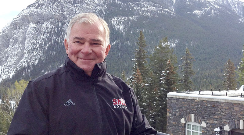 A man standing in front of snow-capped mountains.