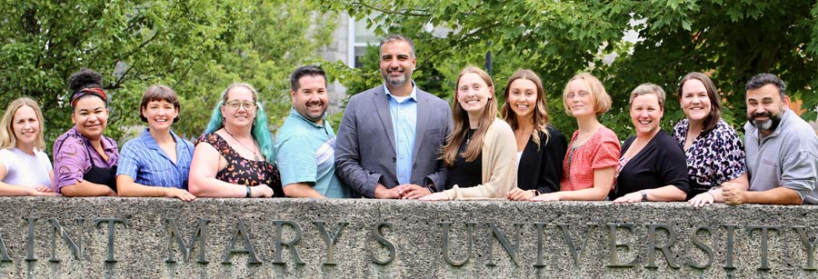 Graduate Diploma in Co-operative and Credit Union Management graduates lined up behind a large, concrete, Saint Marys sign