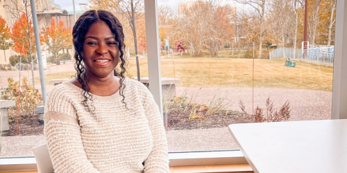 Black Student Advisor sitting in front of window, smiling