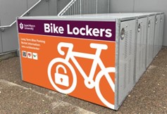 An orange sign on a metal locker reads Bike Lockers